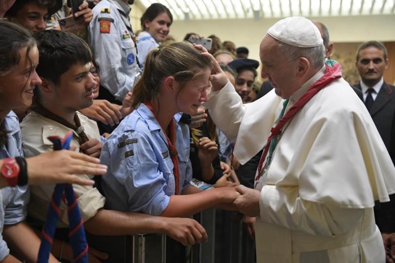 Francisco, con el pañuelo scout, bendice a una joven